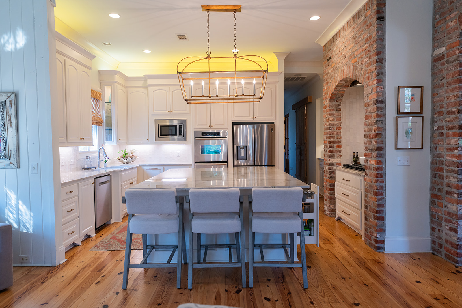 Bright kitchen with large island, open layout, and brick archway